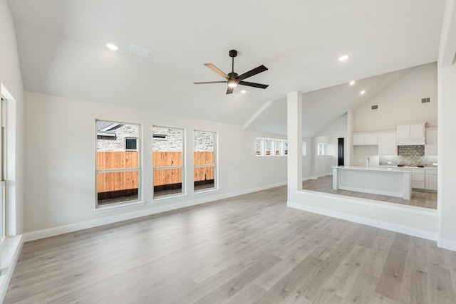 unfurnished living room with ceiling fan, lofted ceiling, sink, and light hardwood / wood-style flooring