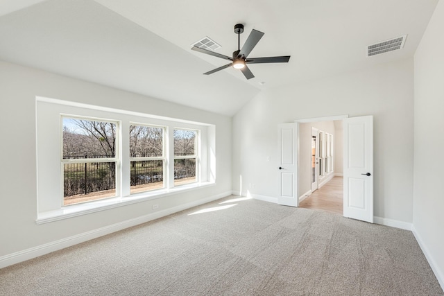 empty room featuring lofted ceiling, light colored carpet, and ceiling fan