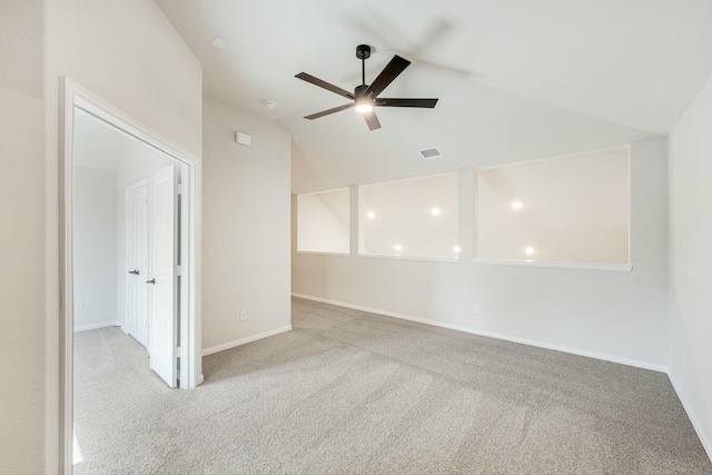 spare room featuring ceiling fan, lofted ceiling, and light carpet