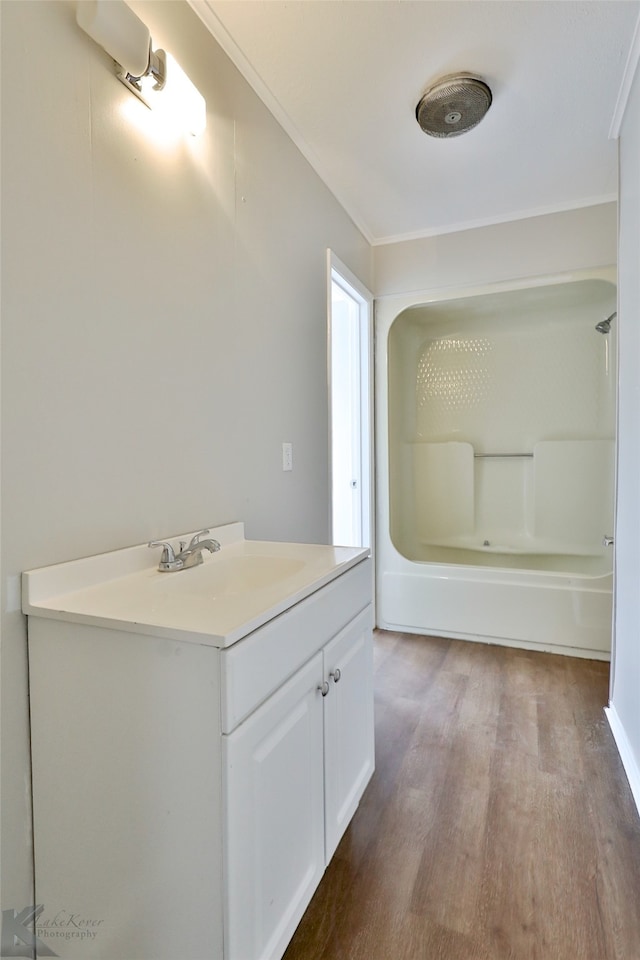 bathroom featuring vanity, hardwood / wood-style floors, bathing tub / shower combination, and ornamental molding