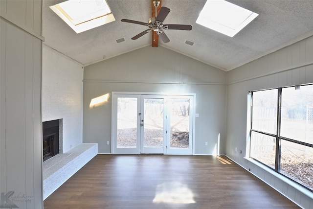 unfurnished living room featuring a large fireplace, a textured ceiling, dark hardwood / wood-style flooring, ceiling fan, and lofted ceiling with skylight