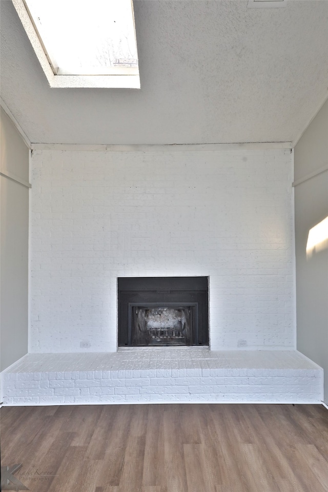 interior details featuring a textured ceiling, hardwood / wood-style flooring, and a brick fireplace