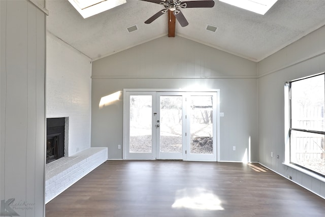 unfurnished living room featuring lofted ceiling with skylight, a fireplace, a healthy amount of sunlight, and dark hardwood / wood-style flooring