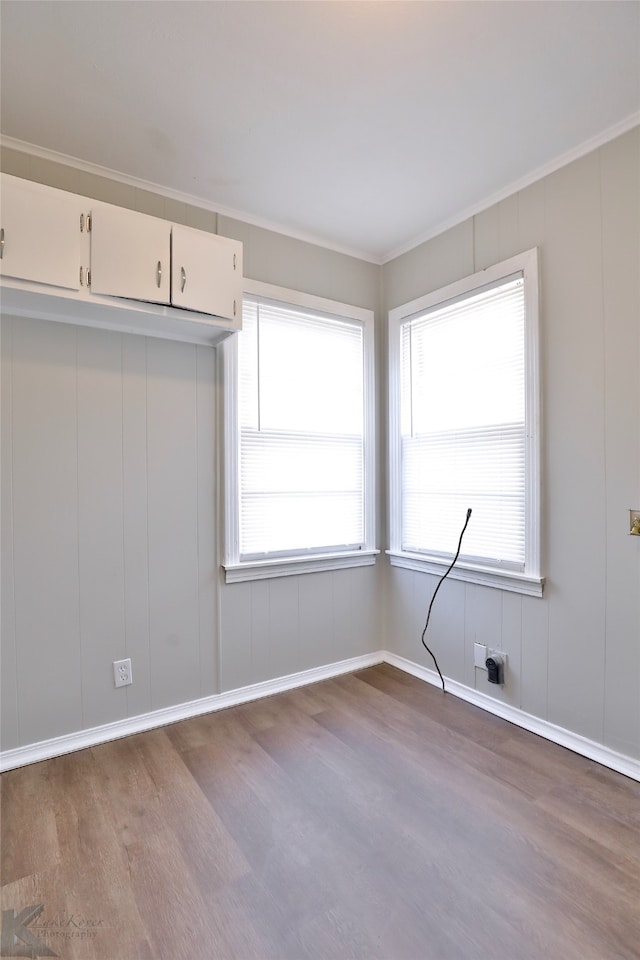 spare room featuring ornamental molding and light wood-type flooring