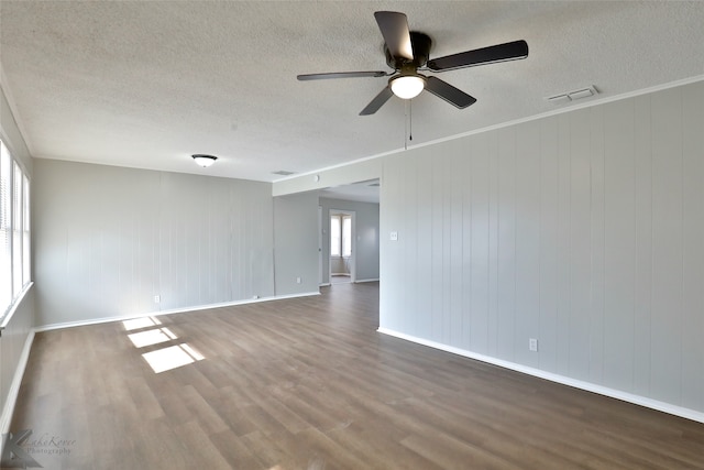 unfurnished room with a wealth of natural light, wooden walls, hardwood / wood-style flooring, and ceiling fan