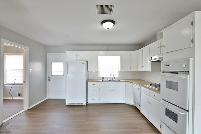 kitchen featuring white appliances, white cabinetry, decorative backsplash, and hardwood / wood-style floors