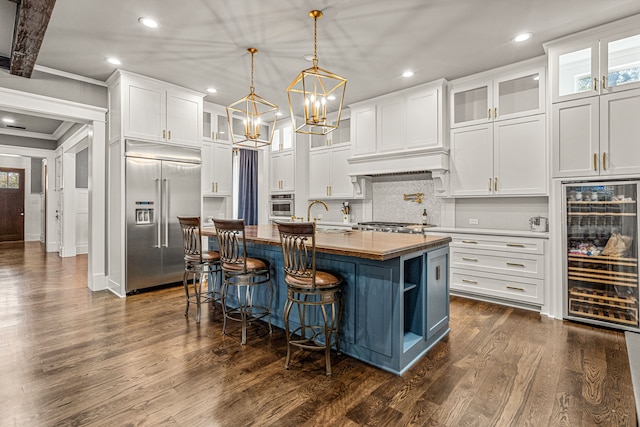 kitchen featuring beverage cooler, dark hardwood / wood-style flooring, stainless steel appliances, white cabinets, and a kitchen island with sink