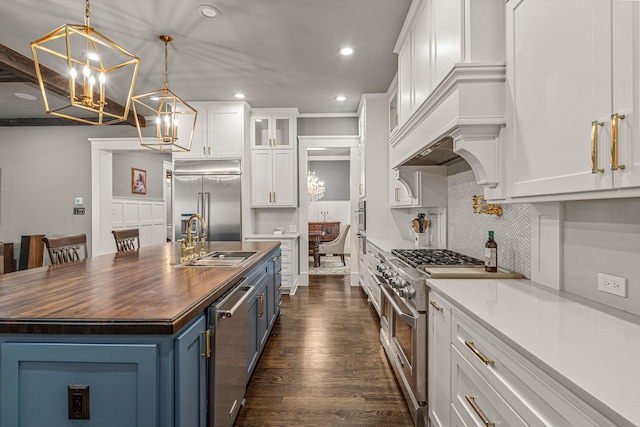 kitchen with a spacious island, white cabinetry, blue cabinetry, butcher block counters, and decorative light fixtures