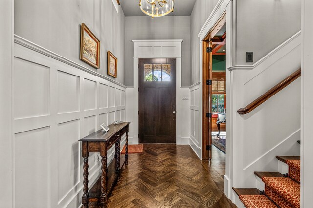 entrance foyer with dark parquet floors, a chandelier, and plenty of natural light