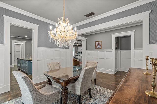 dining area with ornamental molding, sink, and an inviting chandelier