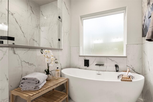 bathroom featuring a washtub, tile walls, and a healthy amount of sunlight