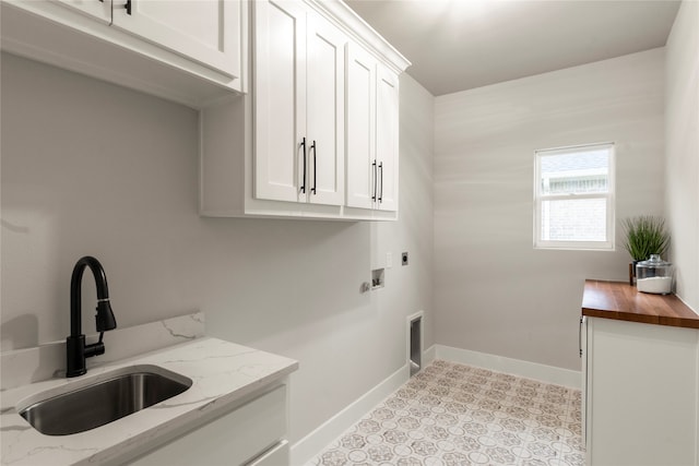 clothes washing area with cabinets, hookup for a washing machine, hookup for an electric dryer, and sink