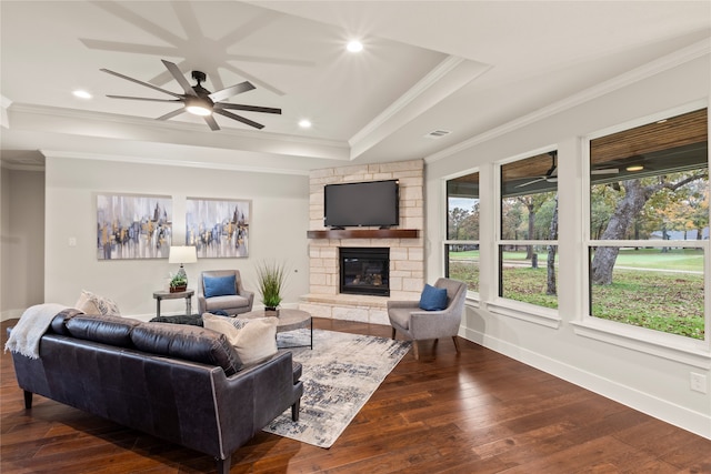 living room with crown molding, a fireplace, ceiling fan, and dark wood-type flooring