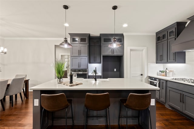 kitchen with stainless steel appliances, a center island with sink, pendant lighting, and dark hardwood / wood-style floors