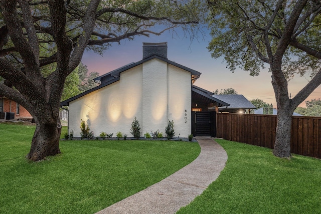 property exterior at dusk featuring cooling unit and a yard