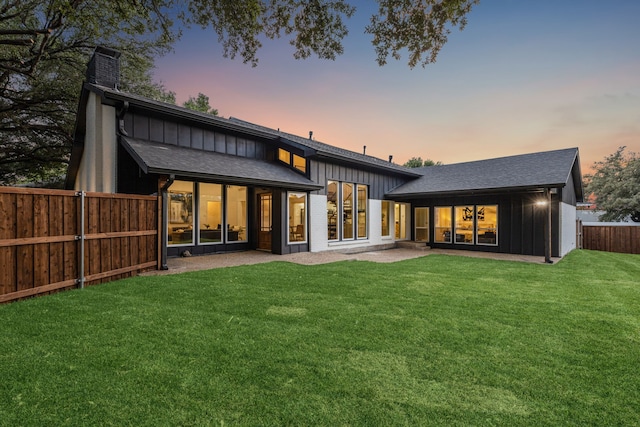 back house at dusk featuring a yard