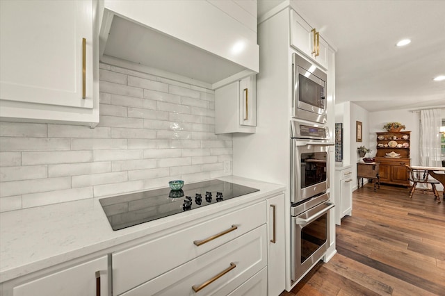 kitchen featuring white cabinetry, appliances with stainless steel finishes, tasteful backsplash, dark hardwood / wood-style flooring, and light stone counters