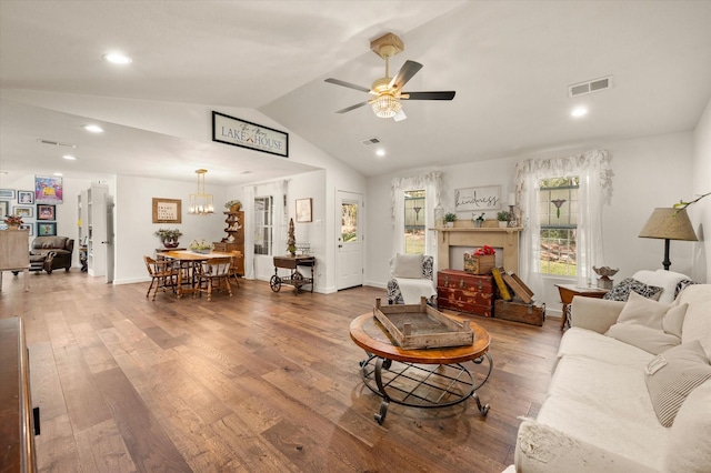 living room with vaulted ceiling, ceiling fan with notable chandelier, and hardwood / wood-style floors