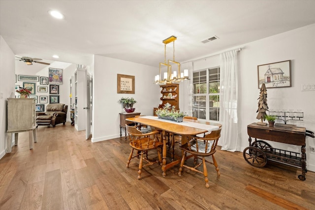 dining room with hardwood / wood-style flooring and ceiling fan with notable chandelier