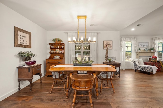 dining area with dark wood-type flooring and an inviting chandelier