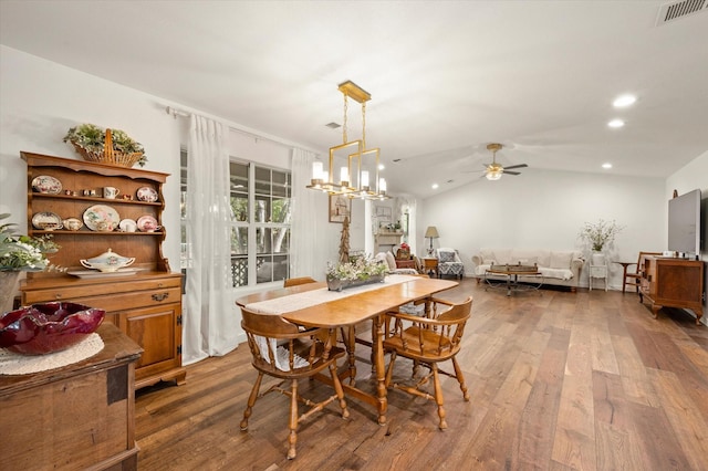 dining area with lofted ceiling, dark hardwood / wood-style floors, and ceiling fan with notable chandelier