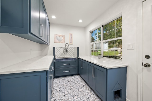 kitchen with kitchen peninsula, blue cabinetry, decorative backsplash, and plenty of natural light