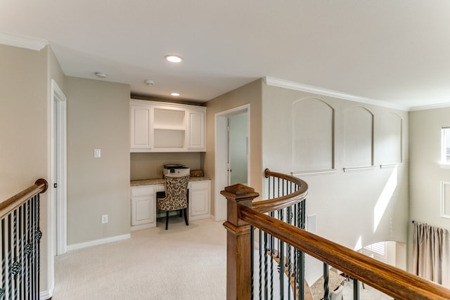 office space featuring light colored carpet, built in desk, and ornamental molding