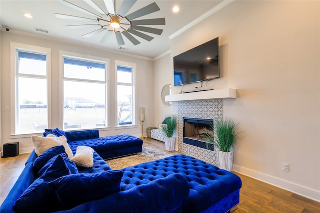 living room with a healthy amount of sunlight, crown molding, hardwood / wood-style flooring, and a fireplace