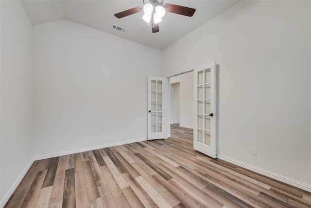 empty room featuring ceiling fan, vaulted ceiling, light hardwood / wood-style floors, and french doors