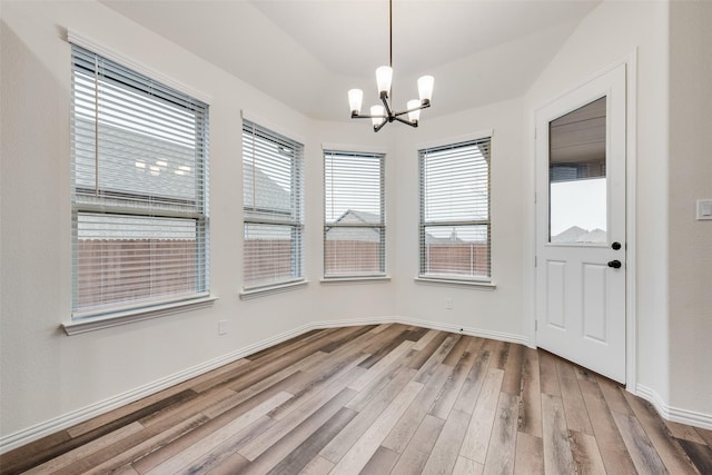 unfurnished dining area with hardwood / wood-style flooring and a chandelier