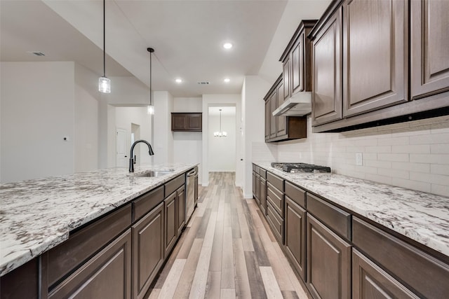 kitchen with dark brown cabinetry, sink, appliances with stainless steel finishes, light hardwood / wood-style floors, and decorative backsplash