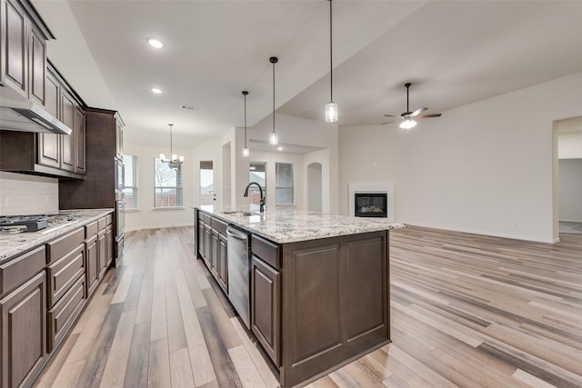 kitchen with appliances with stainless steel finishes, dark brown cabinets, a kitchen island with sink, and decorative light fixtures