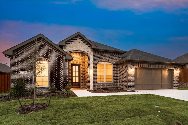 french country inspired facade featuring a garage and a yard