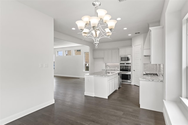 kitchen featuring white cabinets, a center island with sink, appliances with stainless steel finishes, dark hardwood / wood-style floors, and pendant lighting