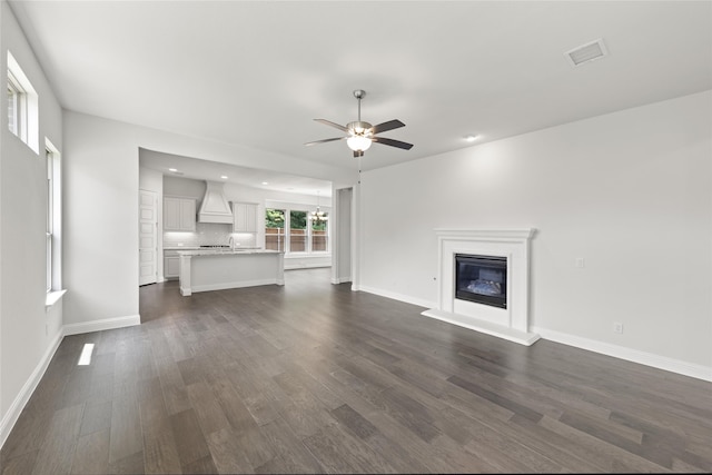 unfurnished living room with sink, dark wood-type flooring, and ceiling fan