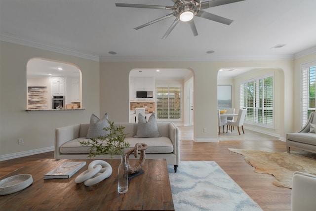 living room featuring crown molding, light hardwood / wood-style flooring, and ceiling fan