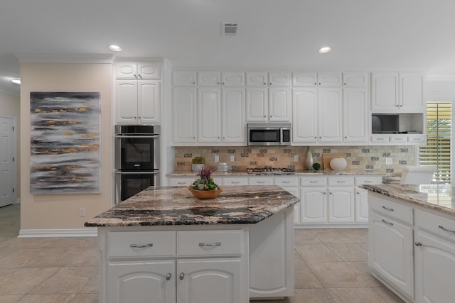 kitchen with white cabinetry, stone countertops, stainless steel appliances, and tasteful backsplash