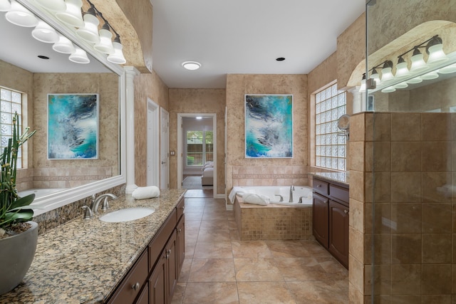 bathroom with vanity, tiled bath, tile patterned floors, and tile walls