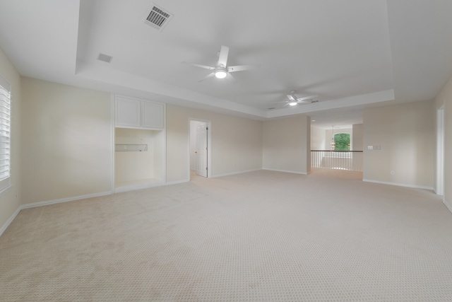 interior space featuring ceiling fan, light colored carpet, and a raised ceiling