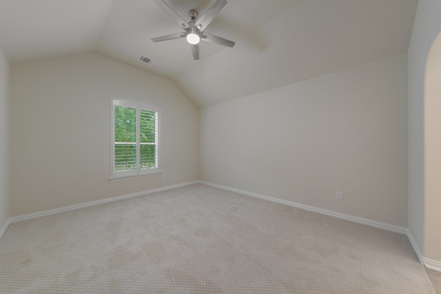 empty room featuring vaulted ceiling, light colored carpet, and ceiling fan