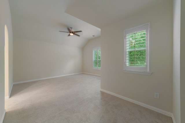 spare room with ceiling fan, light colored carpet, and vaulted ceiling