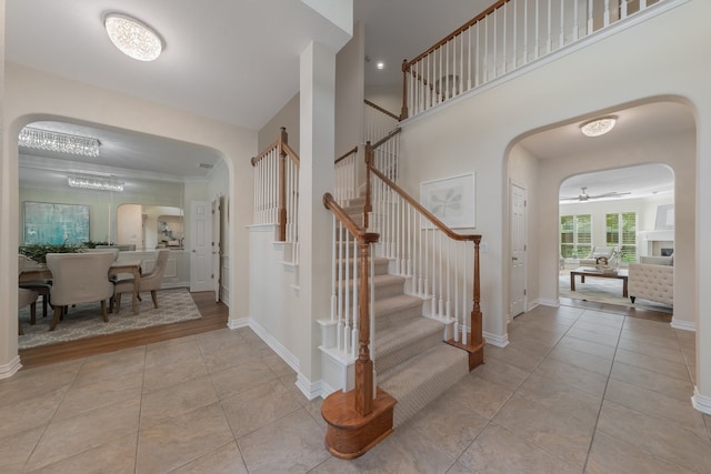 tiled foyer with crown molding, a fireplace, and ceiling fan