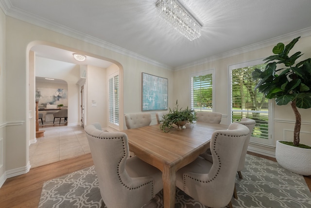 dining space featuring light hardwood / wood-style floors, ornamental molding, and a chandelier