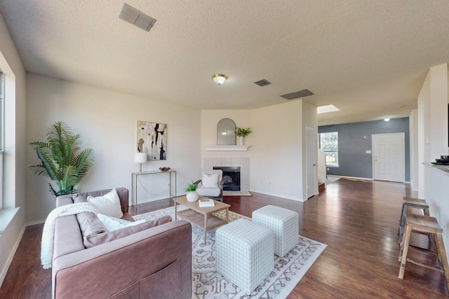 living room with dark wood-type flooring, a textured ceiling, and a fireplace