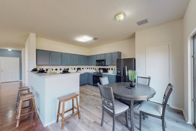 kitchen featuring light hardwood / wood-style flooring, a textured ceiling, and black appliances