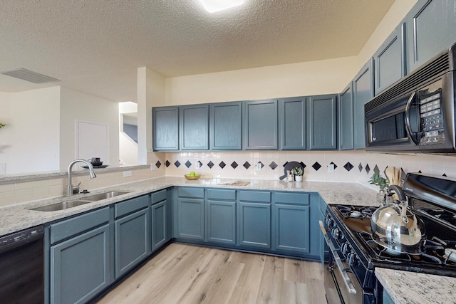 kitchen with black appliances, sink, backsplash, a textured ceiling, and light hardwood / wood-style floors