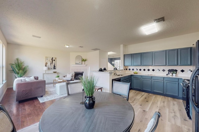 dining space with light hardwood / wood-style flooring, a textured ceiling, a tiled fireplace, and sink