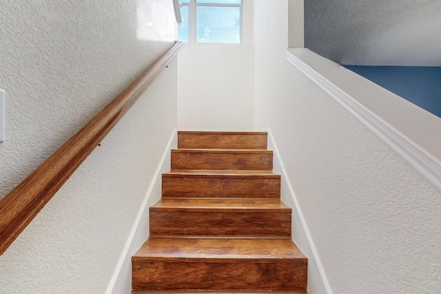 stairway featuring a textured ceiling