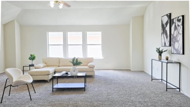 carpeted living room featuring ceiling fan and vaulted ceiling