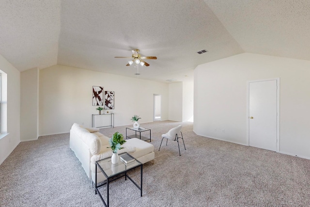 living room with lofted ceiling, a textured ceiling, light colored carpet, and ceiling fan